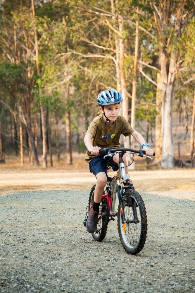 Nine year old boy riding pushbike with helmet and boots on - Australian Stock Image