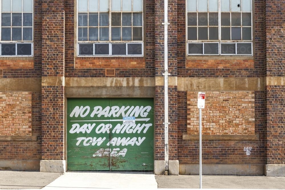 Image of No parking sign on green door of historic factory in