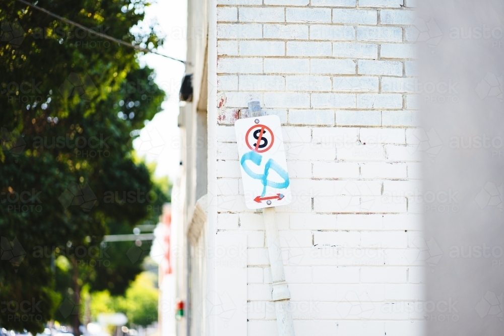 No standing sign with graffiti on white brick wall background - Australian Stock Image