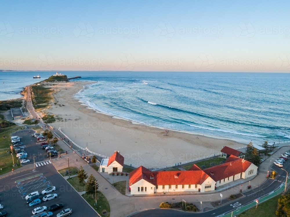 Nobbys Beach Surf Pavilion with sunset light on red building roof and view over ocean in Newcastle - Australian Stock Image