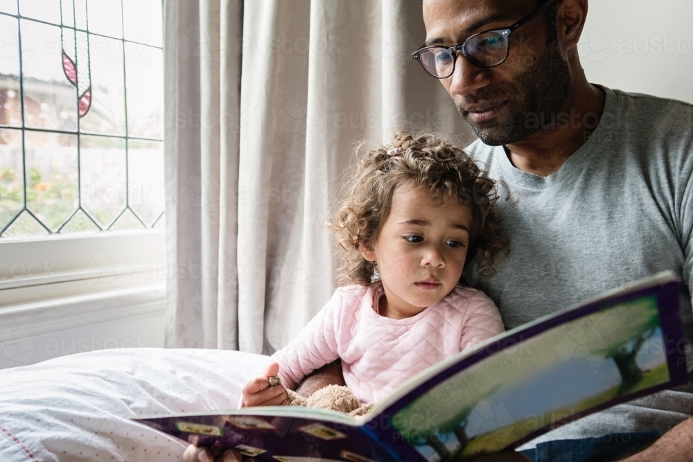Father reading daughter a story book - Australian Stock Image