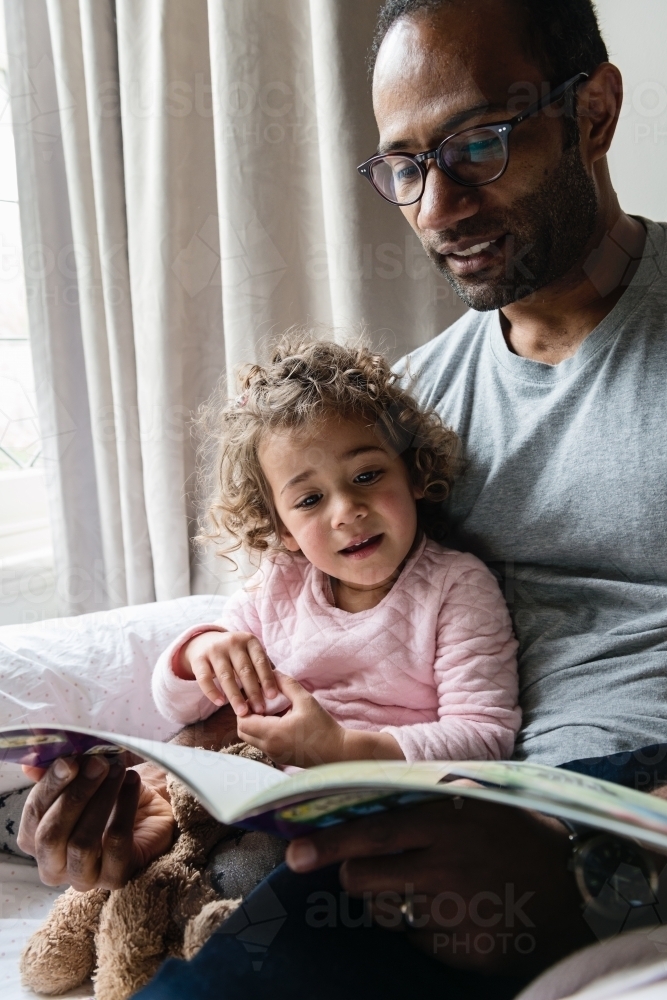Daddy and little girl reading a story together - Australian Stock Image