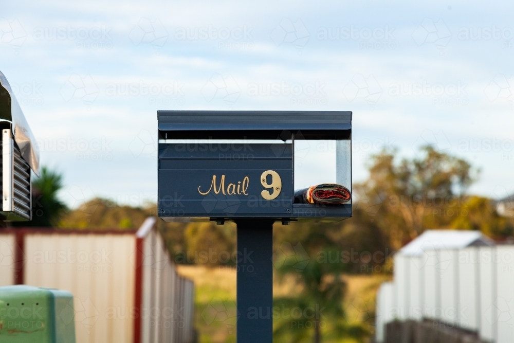 Number 9 mail box in front of long driveway with junk mail catalog - Australian Stock Image