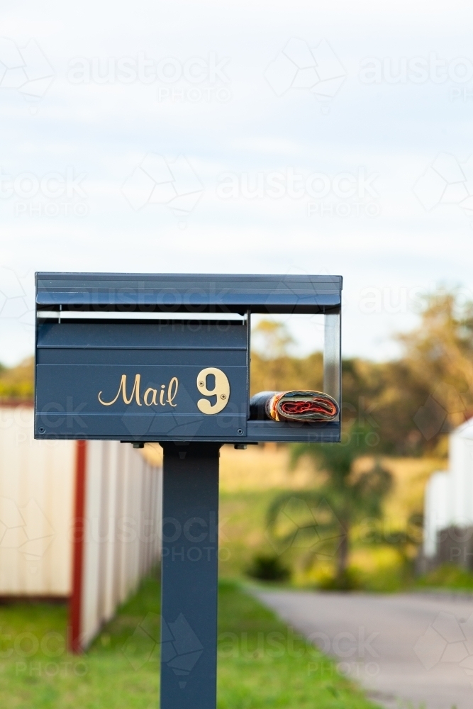 Number 9 mail box in front of long driveway with junk mail catalog - Australian Stock Image