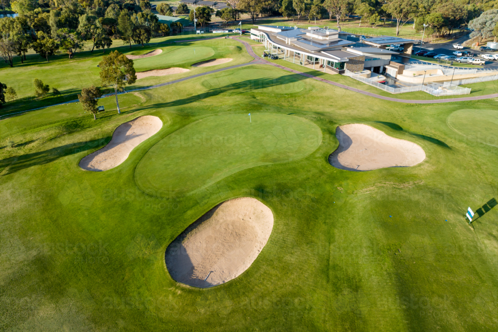 oblique aerial view of golf green with bunkers and clubhouse - Australian Stock Image