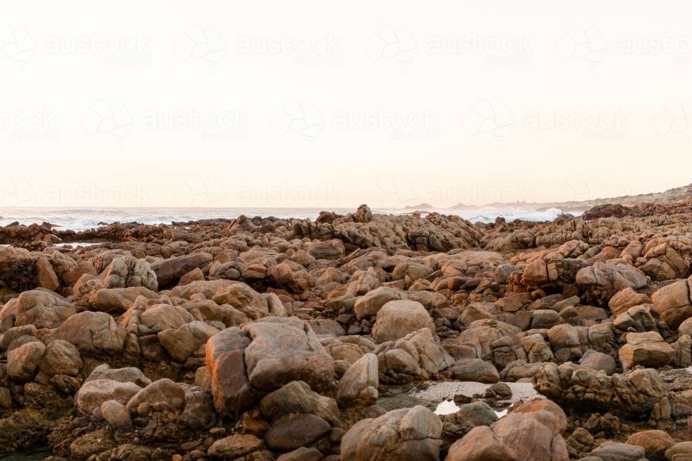 Ocean and rock view of rugged coastline at sunset - Australian Stock Image