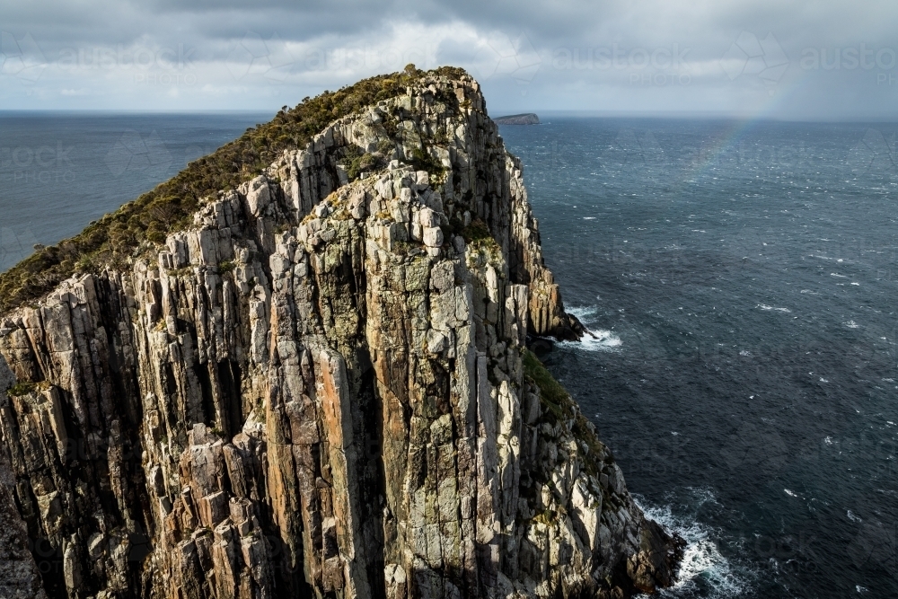 Ocean scene with rocky cliffs, a headland and rainbow - Australian Stock Image