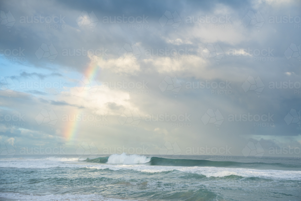 Ocean seascape with distant rainbow appearing over coastal water at Scarborough Beach, Perth - Australian Stock Image