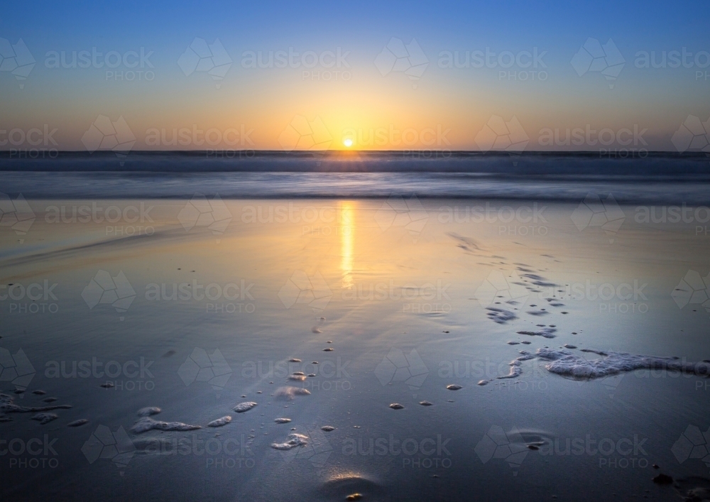 Ocean sunrise over wet sand - Australian Stock Image