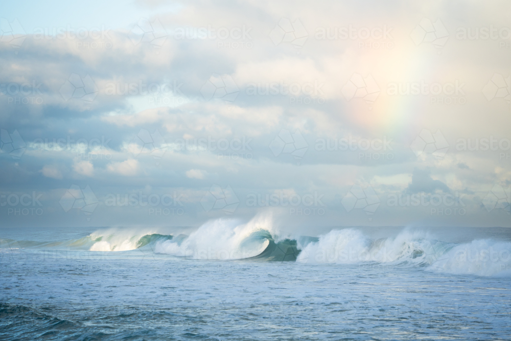 Ocean wave crashing with sun flare creating mist spray at Scarborough Beach, Perth - Australian Stock Image