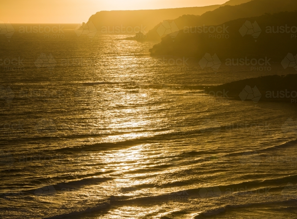 Ocean waves, headlands and sea mist in golden sunset light - Australian Stock Image