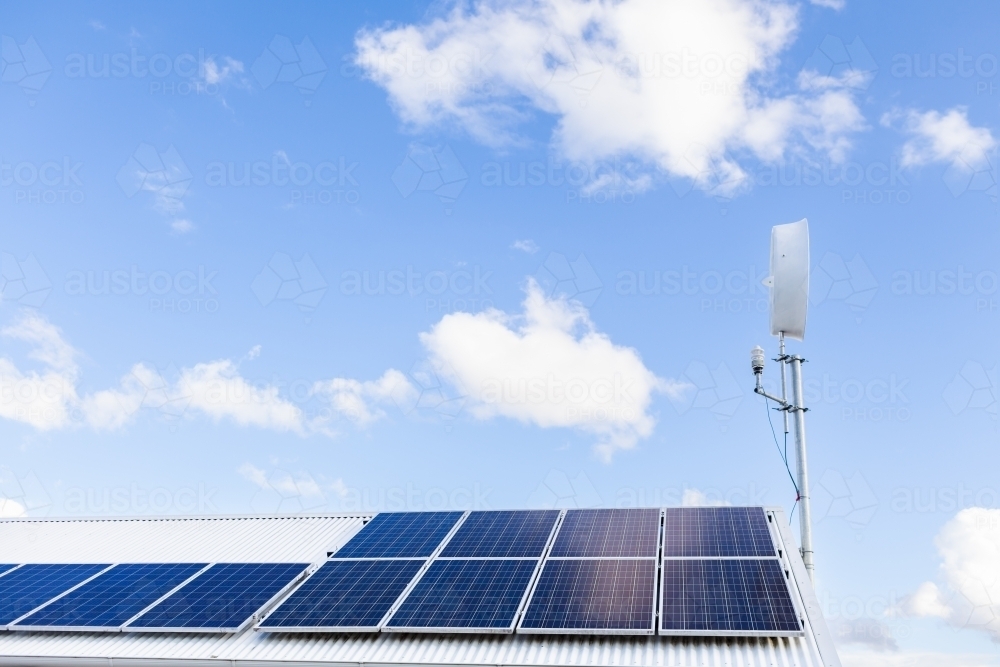 off grid sustainable living with solar panels and wind turbine on shed roof - Australian Stock Image