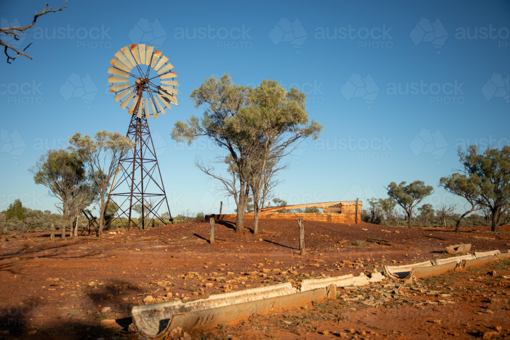 Old abandoned windmill and turkey nest with trough in the foreground - Australian Stock Image