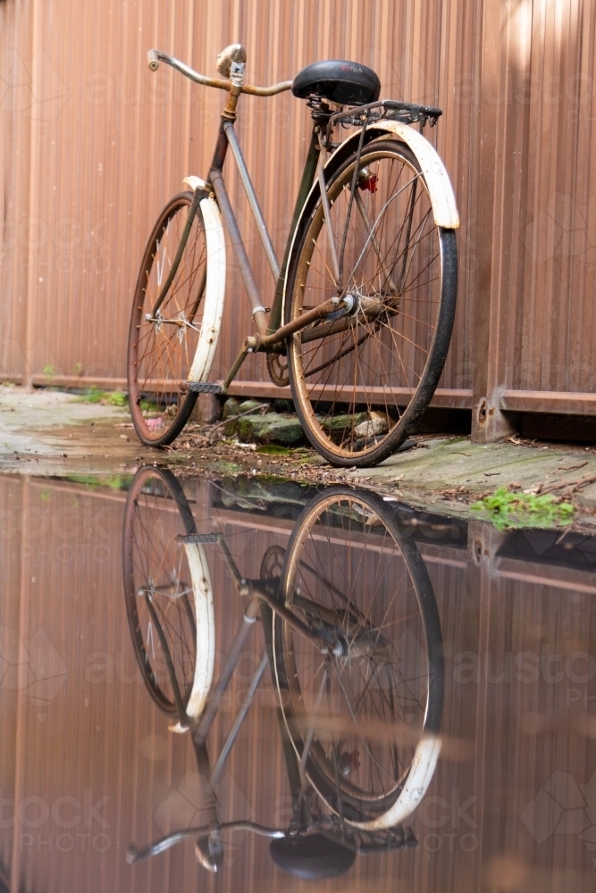Old bicycle and reflection against corrugated iron fence - Australian Stock Image