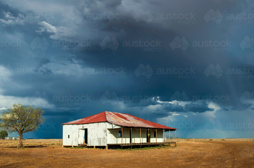 Old corrugated shed with a rusted roof beneath a brooding outback storm sky. - Australian Stock Image