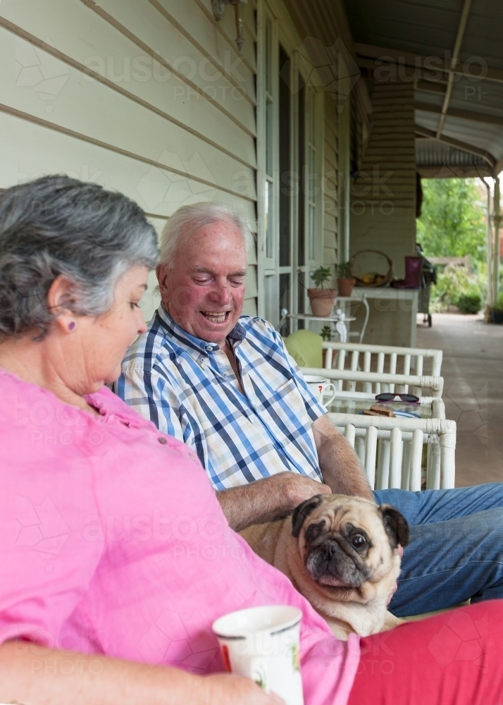 Old couple sitting on the front porch with their pet dog - Australian Stock Image