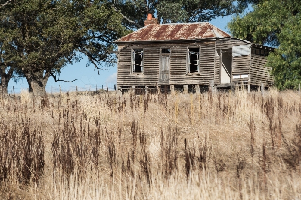Old farm cottage on hill in dry country paddock - Australian Stock Image