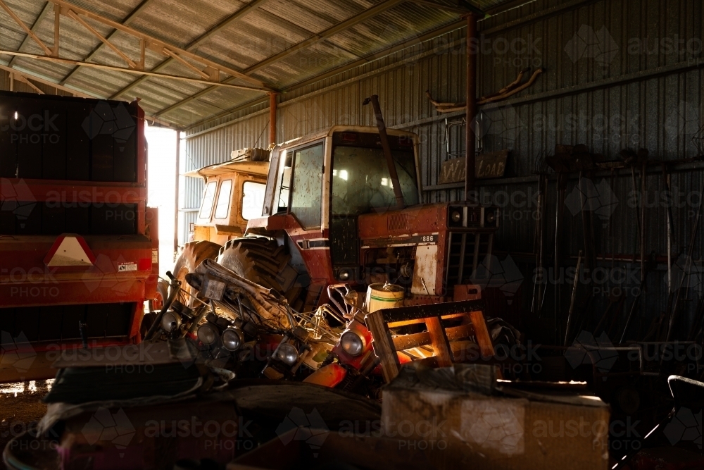 Old farm machinery parked in dark shed left to rust and forgotten in time - Australian Stock Image