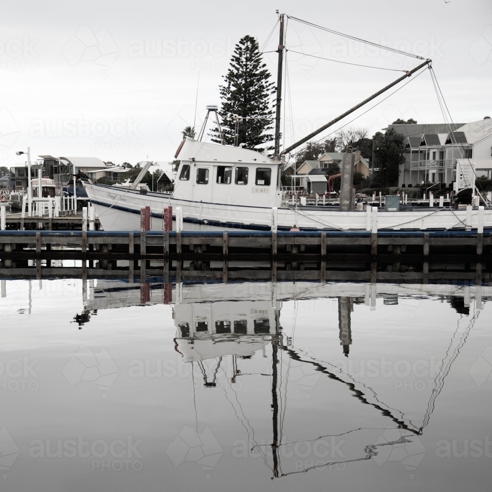 old fishing boat with reflection in the water at marina - Australian Stock Image
