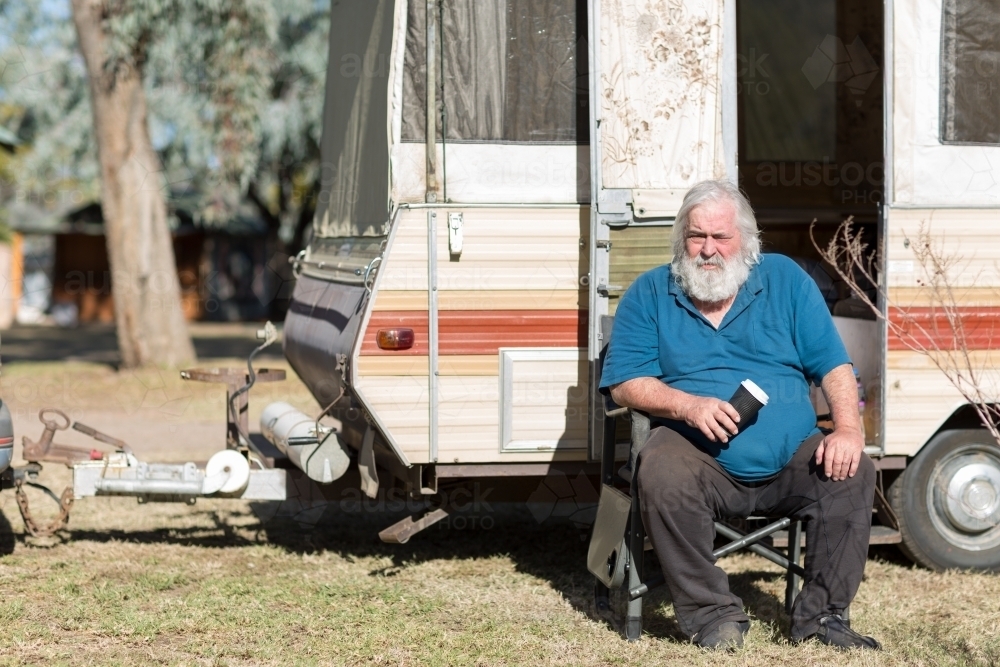 Old guy sitting outside his vintage caravan - Australian Stock Image