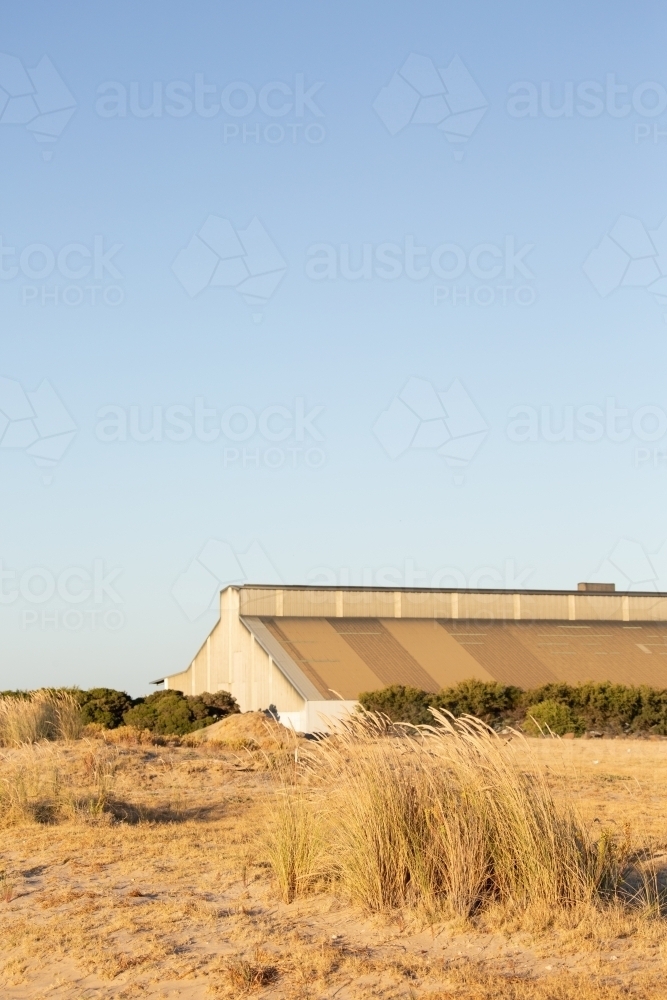 old industrial building at the port obscured in sand dunes - Australian Stock Image