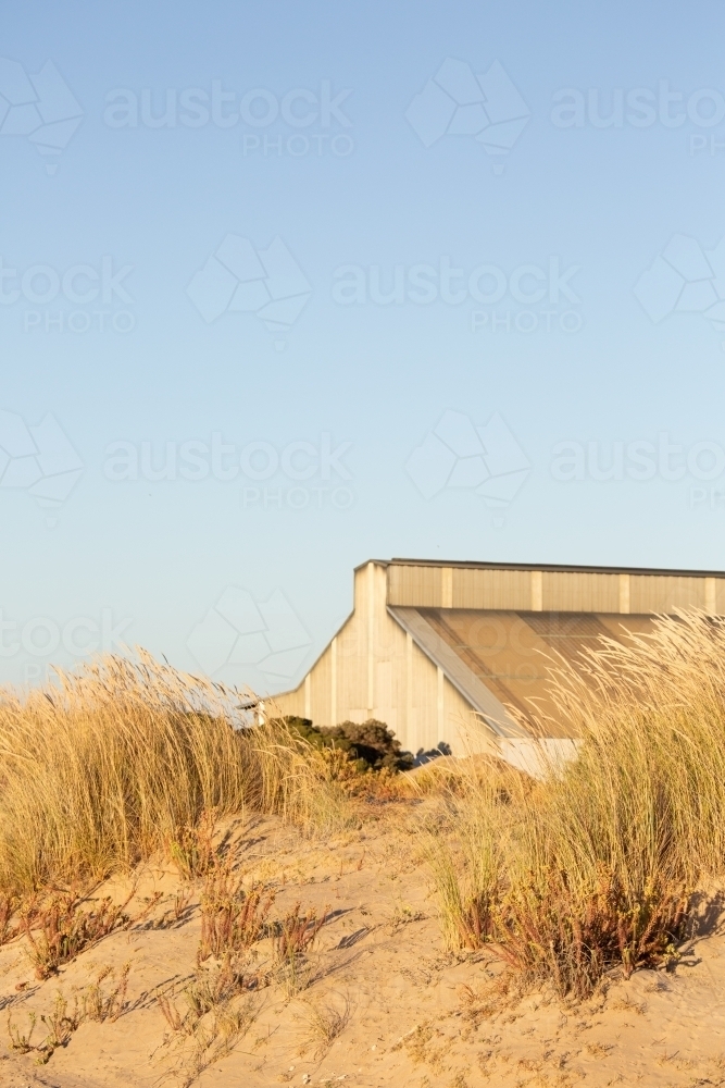 old industrial building at the port obscured in sand dunes - Australian Stock Image
