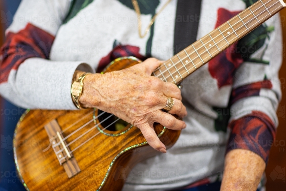 old lady's hand holding ukulele - Australian Stock Image