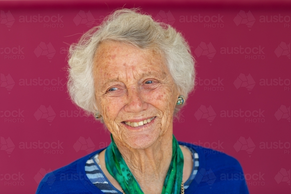 old lady with grey hair looking away away against a plain background - Australian Stock Image