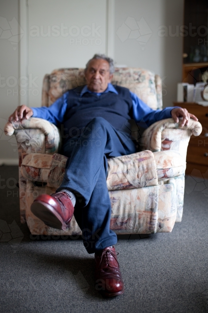 Old man sitting in lounge chair - Australian Stock Image