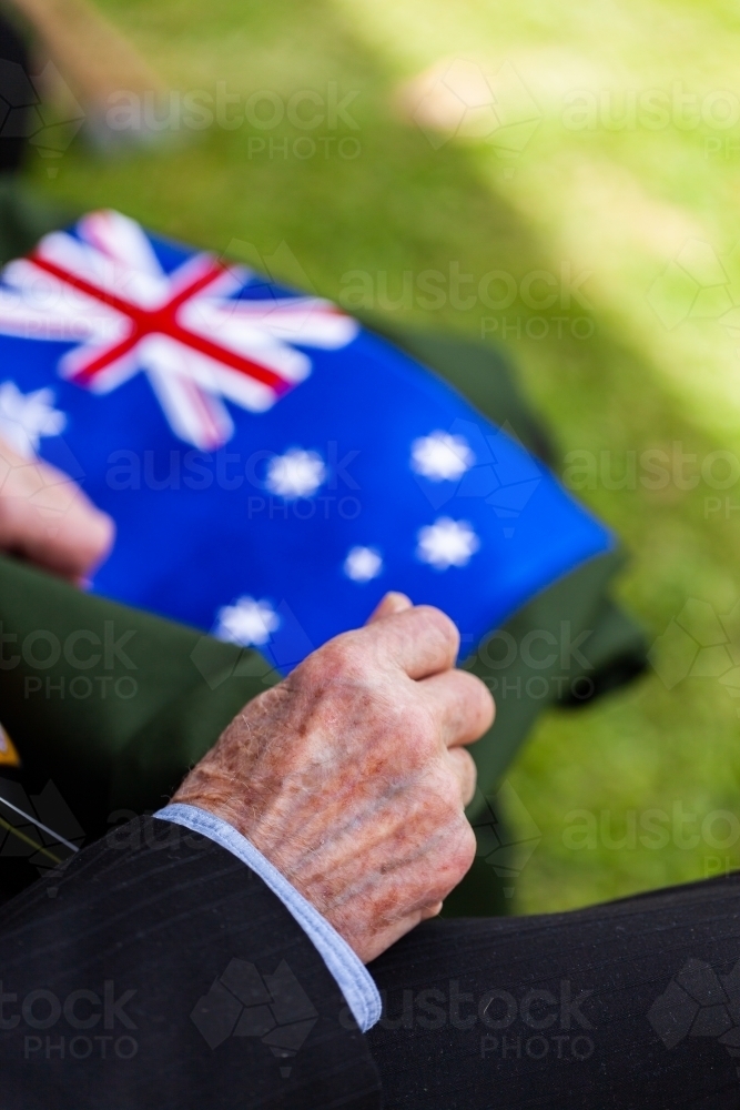 old mans hands resting beside australian flag at remembrance day ceremony - Australian Stock Image