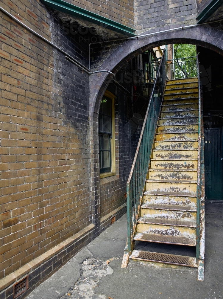 Old metal stairway under brick arch - Australian Stock Image