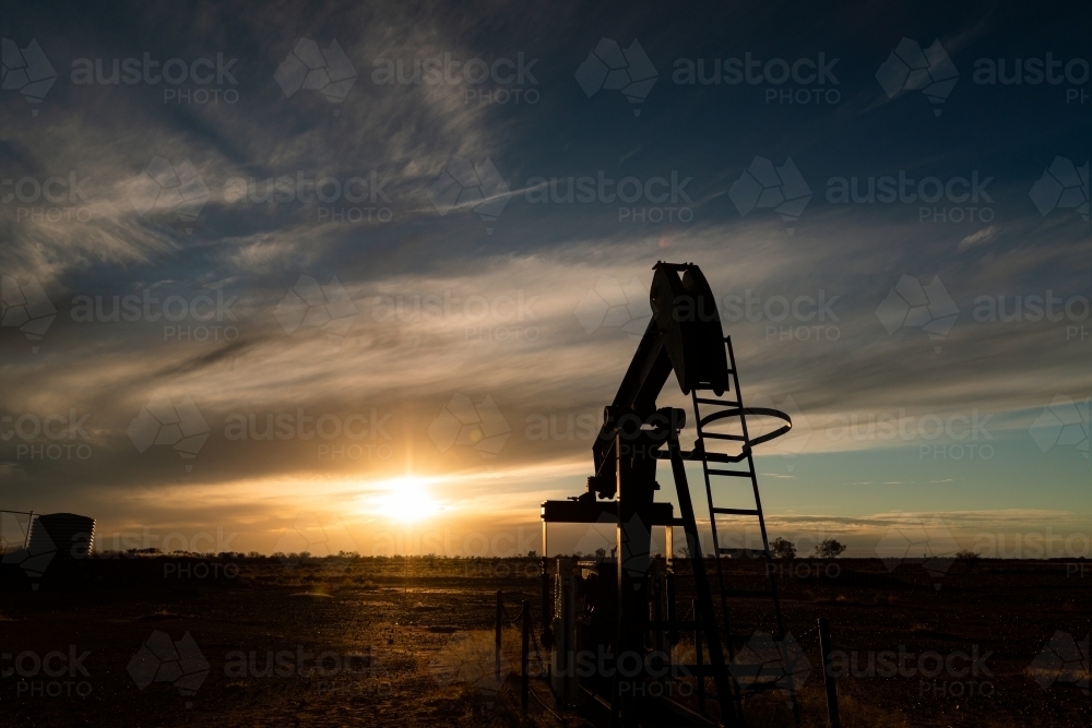 Old nodder or pumpjack from the gas fields silhouetted in the sunset - Australian Stock Image