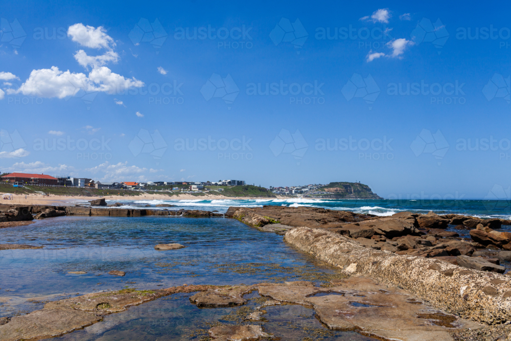 Old ocean pool carved from rocks at the beach on sunlit summers day along Australian coast - Australian Stock Image