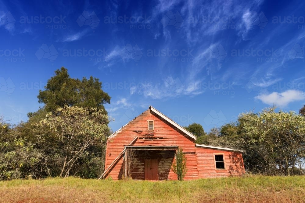 Old orange wooden shed left deserted in a paddock - Australian Stock Image