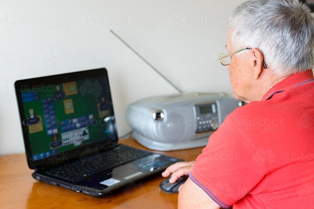 Old person playing games on a laptop - Australian Stock Image