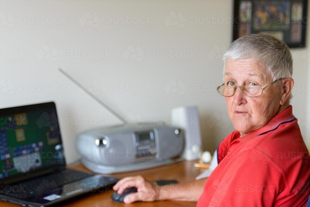 Old person using laptop and looking at camera - Australian Stock Image
