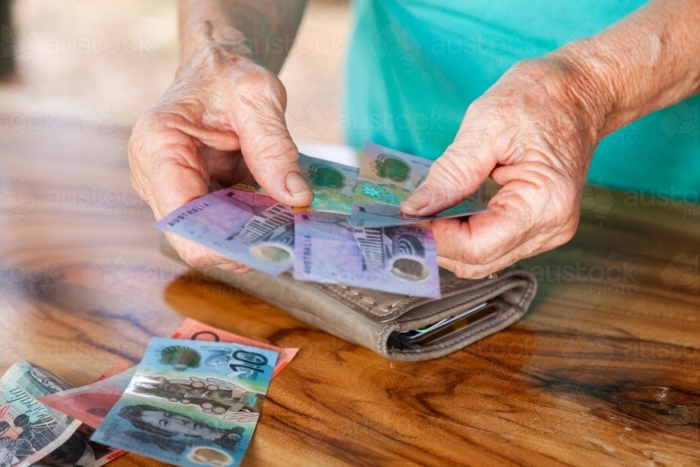 Old persons hands handing over australian bank notes - Australian Stock Image