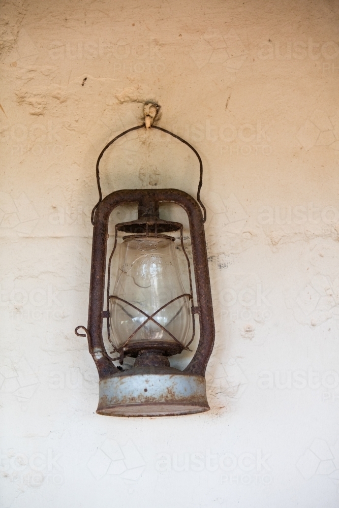 Old pioneer lantern hanging on a white stone wall - Australian Stock Image