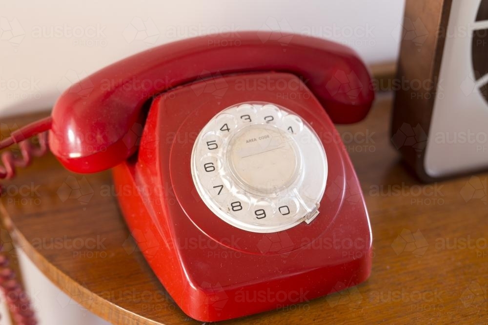 Old red rotary telephone on sideboard - Australian Stock Image