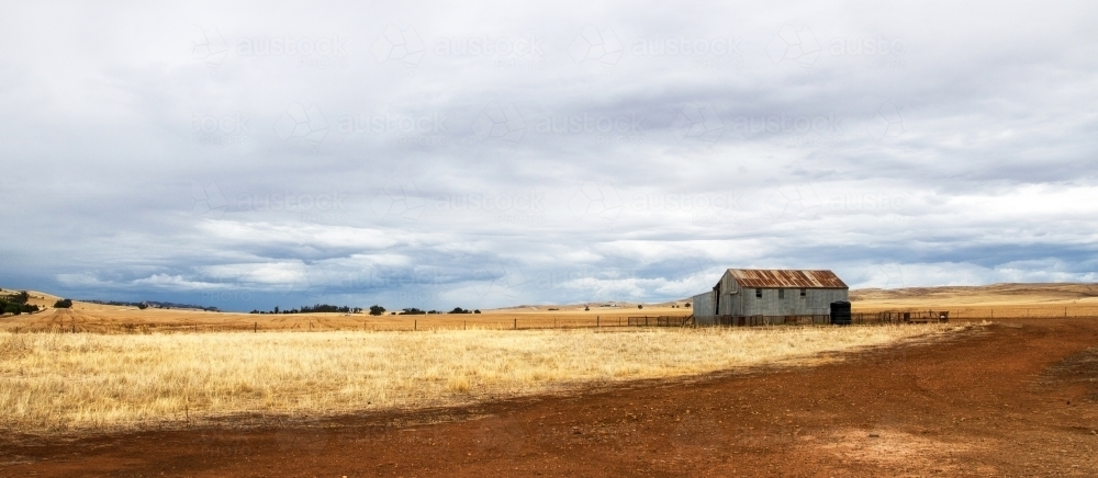 Old rusted shed in stubble paddock - Australian Stock Image