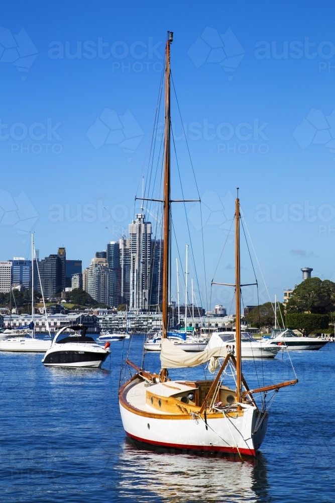 Old sailboat moored with city in background - Australian Stock Image