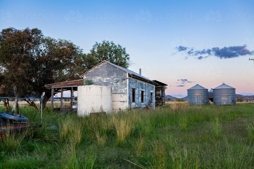 Image of Old tank and shearers hut beside shed and silos on australian