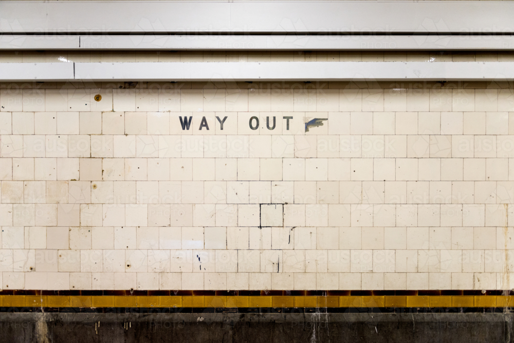 Old tiled wall with a weathered 'Way Out' sign in an underground train station - Australian Stock Image