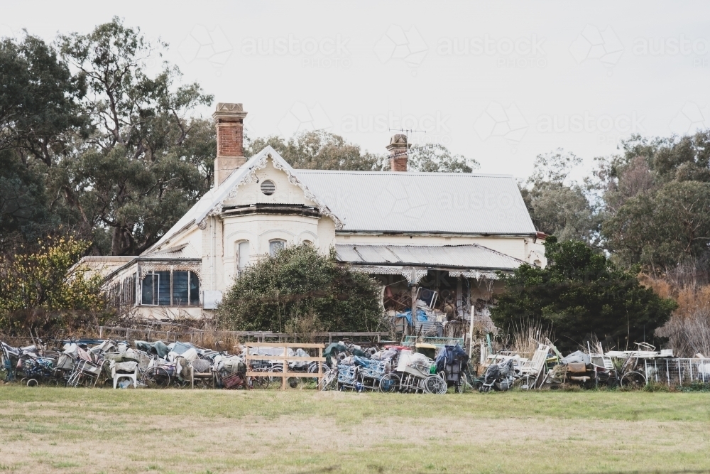 Old victorian house with a lot of used items or junk surrounding it . - Australian Stock Image