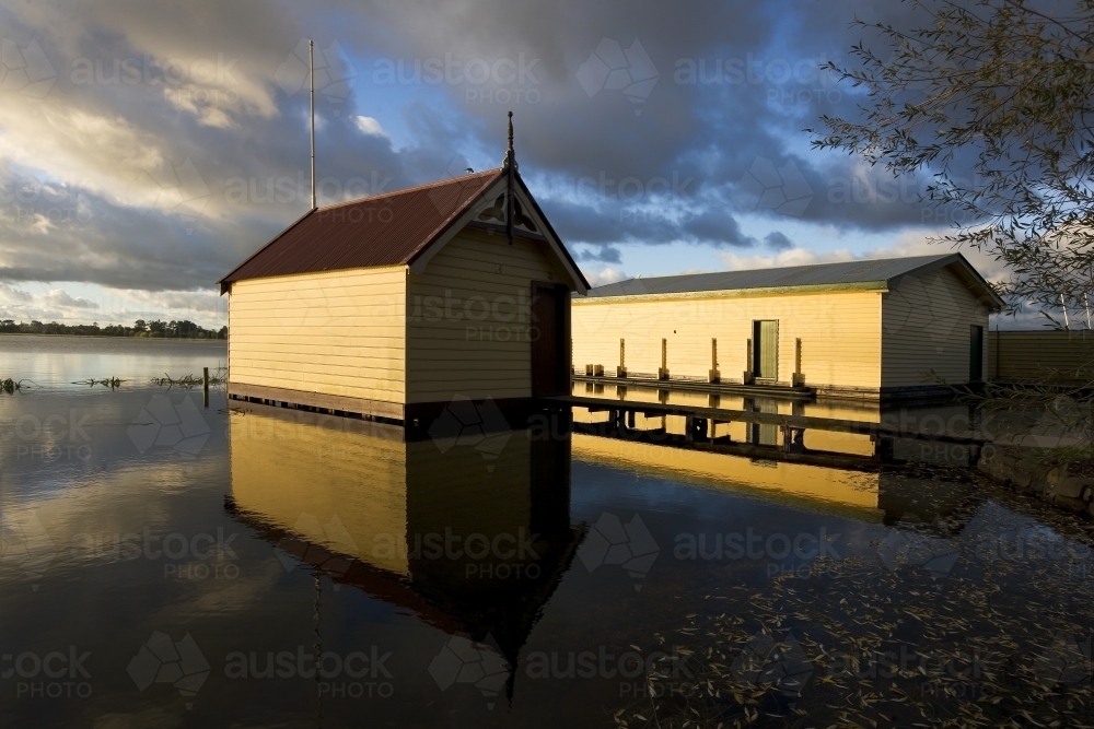 Old weatherboard boat sheds on calm lake - Australian Stock Image