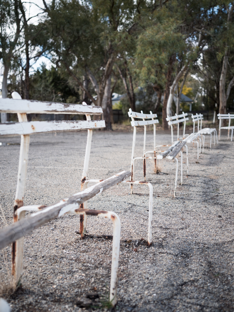Old white wooden benches on an asphalt path - Australian Stock Image