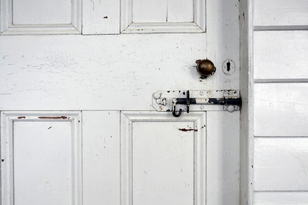 Old white wooden door with bolt lock and brass door handle - Australian Stock Image