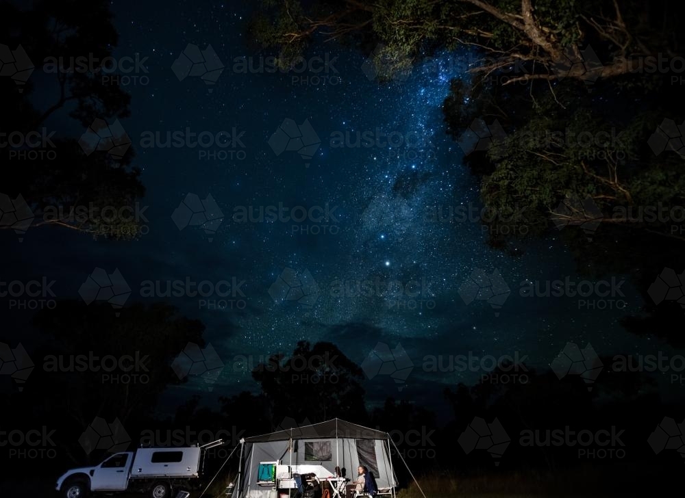 Old woman sitting at a campsite in remote, rugged setting - Australian Stock Image