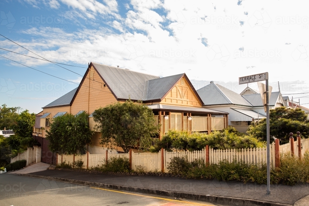 Old yellow house with a steep roof on a corner in Paddington, Brisbane - Australian Stock Image