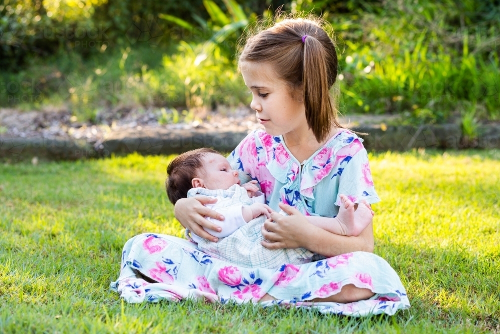 Image of Older child cuddling young baby girl outside - loving family ...